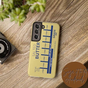 May include: A yellow phone case with a stick of butter design. The case has a blue label that reads "Salted Butter" and includes measurements in tablespoons and cups. The label also includes the text "Grade AA" and "Not for individual sale".