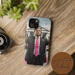 May include: A phone case with a cartoon image of a man in a suit and tie, standing in front of a building. The text "Daddy's Home" is written on the case.