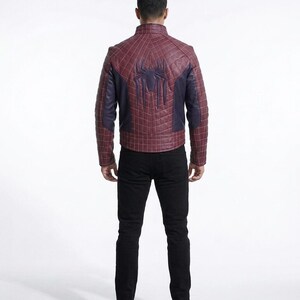 Peut inclure: Une veste bordeaux et bleu fonc&eacute; avec un motif quadrill&eacute; matelass&eacute; et un embl&egrave;me d'araign&eacute;e sombre bien visible dans le dos. La veste pr&eacute;sente un col montant et des manches longues, port&eacute;e avec un pantalon noir et des chaussures noires.