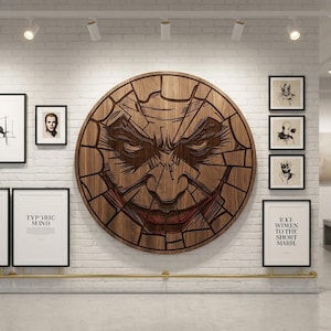 Puede incluir: Una gran obra de arte mural circular de madera con una talla detallada de la cara de un personaje con una sonrisa siniestra. La obra está montada en una pared de ladrillo blanco, rodeada de obras de arte enmarcadas.