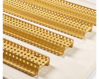 Puede incluir: Tres piezas alargadas de moldura para muebles en forma de L con un patrón de rejilla de mimbre tejido en color tostado claro natural. Cada pieza tiene una estructura rígida con una textura perforada y un perfil en ángulo recto.