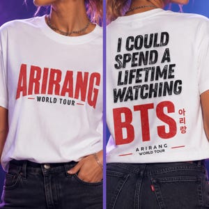Peut inclure: T-shirt blanc avec l'inscription rouge "ARIRANG - WORLD TOUR" sur le devant. Le dos du t-shirt porte l'inscription "I COULD SPEND A LIFETIME WATCHING BTS" en noir et rouge, avec des caract&egrave;res cor&eacute;ens et "ARIRANG WORLD TOUR".