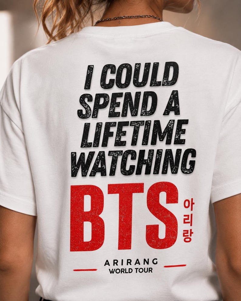 Peut inclure: T-shirt blanc avec l'inscription "I COULD SPEND A LIFETIME WATCHING BTS" en noir, police vieillie. Le mot "BTS" est en rouge, avec des caract&egrave;res cor&eacute;ens et "ARIRANG WORLD TOUR" en dessous.