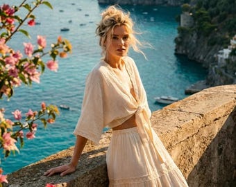 May include: A two-piece set consisting of a cream-colored, short-sleeved, tie-front top and a matching tiered midi skirt. The garment features delicate lace trim detailing along the hem of the sleeves and the horizontal tiers of the skirt.