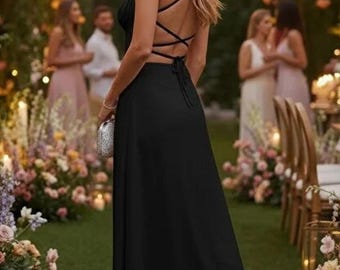 May include: A floor-length black dress featuring a sleeveless bodice with a crisscross lace-up back design, a tie closure at the waist, and a long, flowing skirt. The garment is paired with a small, metallic silver clutch handbag.