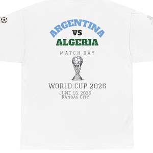 Può includere: T-shirt bianca con la scritta "ARGENTINA VS ALGERIA MATCH DAY" e una grafica della Coppa del Mondo 2026. La maglietta include anche la data 16 giugno 2026 e la località di Kansas City.