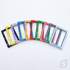 May include: A collection of ten rectangular frames arranged in a fan shape. Each frame features a distinct solid color including black, yellow, purple, blue, orange, red, green, pink, gray, and light blue, all with a textured geometric pattern.
