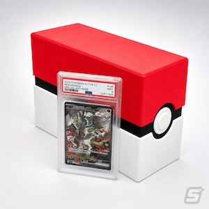 May include: A PSA graded 2025 Pokemon SV11W CT Reshiram ex Special Art Rare trading card in a clear plastic slab, positioned in front of a rectangular storage box designed with red, white, and black colors resembling a classic Poke Ball.