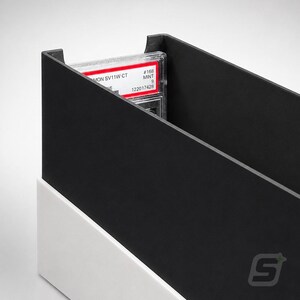 May include: A black and white storage box for trading cards featuring a rectangular design with an open top. Inside the box, a single graded trading card in a clear plastic slab is visible, displaying the text MON SV11W CT, #168, MINT 9, 122017428.