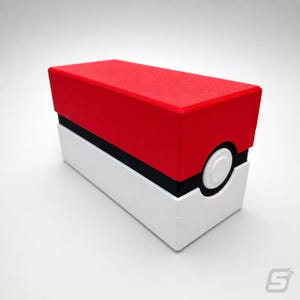 May include: A rectangular box with a red top, white base, and black stripe. The box has a white circular button on the side. The design is reminiscent of a popular animated series.