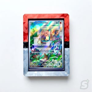May include: A holographic Charmander trading card encased in a rectangular frame designed like a red, white, and black Poké Ball. The card features an illustration of a Charmander looking through a window with a bird perched on the sill.