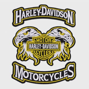 May include: A set of three embroidered patches featuring the Harley-Davidson logo. The top arch reads Harley-Davidson, the center shows two eagle heads flanking a shield with Motor Harley-Davidson Cycles, and the bottom arch reads Motorcycles.