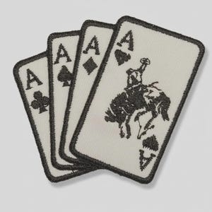 May include: A set of four rectangular embroidered patches featuring playing card designs. Each patch has a white background with black stitched borders and details, including the ace of clubs, spades, diamonds, and a cowboy on a bucking horse.