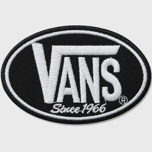 May include: An oval-shaped embroidered patch featuring a black background with a white border. The white text reads VANS with the word Since 1966 underneath, and a small registered trademark symbol is positioned to the right of the logo.
