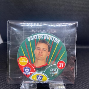Peut inclure: Une carte de sport de collection avec Baxter Norton, avec le texte "BAXTER NORTON" en haut. La carte a un design vert, rouge et jaune avec le numéro 21 dans un cercle rouge. La carte est dans une pochette de protection.