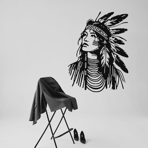 Op de afbeelding: Zwart-wit wandkunst van een inheemse Amerikaanse vrouw met een gevederde hoofdtooi. Het kunstwerk is een minimalistisch ontwerp met strakke lijnen. Een zwarte jas is over een klapstoel gedrapeerd, met zwarte hakken op de vloer.