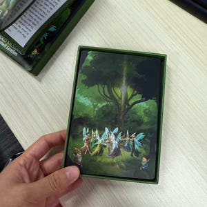 May include: A white ceramic mug with a black handle and the text "But First, Coffee" in a black, handwritten-style font. The mug is on a white surface.