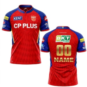 Könnte beinhalten: Rotes und blaues kurzärmeliges Trikot mit dem Text "KENT" und "CP PLUS" auf der Vorderseite. Auf der Rückseite des Trikots stehen die Nummer "00" und das Wort "NAME" in Gold. Das Trikot hat auch Sponsorenlogos.