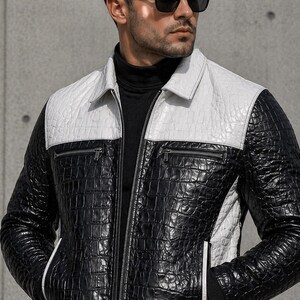 Puede incluir: Chaqueta de cuero en blanco y negro con un patrón texturizado similar al de un cocodrilo. La chaqueta presenta una parte superior del pecho y los hombros blancos, un cuerpo negro y cierre de cremallera. Cuello con solapas y dos bolsillos delanteros.