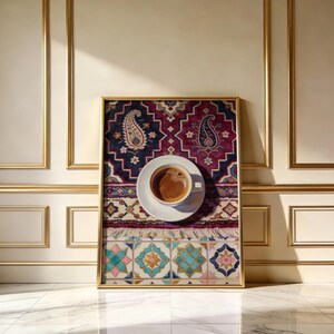 May include: A framed print featuring a cup of coffee on a saucer, set atop a patterned rug with paisley and geometric designs. The rug's colors include deep reds, blues, and turquoise, framed in gold.