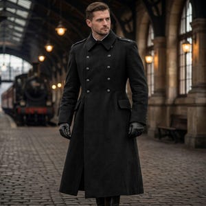 May include: A long, black wool coat with a double-breasted design, featuring large buttons and a tailored fit. The coat has a high collar and is worn with black gloves. The background shows a train station with a vintage train.