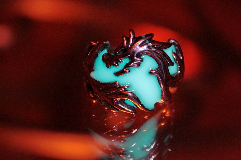 Peut inclure: Une bague en argent avec un motif de dragon. Le corps du dragon est rempli d'une r&eacute;sine turquoise qui brille.