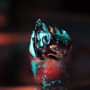 Peut inclure: Une bague en argent avec une pierre bleu turquoise sertie dans un motif en forme de flamme.