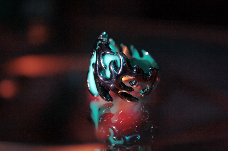 Peut inclure: Une bague en argent avec une pierre bleu turquoise sertie dans un motif en forme de flamme.