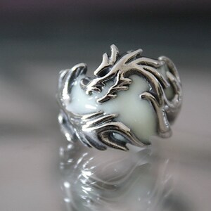 Peut inclure: Une bague en argent avec un motif de dragon en &eacute;mail blanc. Le dragon est enroul&eacute; autour d'un centre en &eacute;mail blanc.