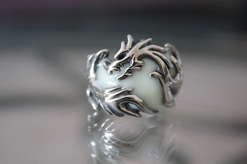 Peut inclure: Une bague en argent avec un motif de dragon en &eacute;mail blanc. Le dragon est enroul&eacute; autour d'un centre en &eacute;mail blanc.