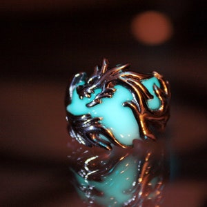 Peut inclure: Une bague en argent avec un motif de dragon vert brillant. Le dragon est enroul&eacute; autour d'une pierre verte.