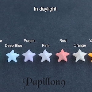 May include: A collection of star-shaped beads in various colors, including green, turquoise, deep blue, purple, pink, red, orange, yellow, and white. The image includes the text "In daylight" and the brand name "Papillong".