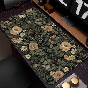 May include: A rectangular desk mat featuring a floral pattern with large peach-colored flowers, smaller yellow flowers, and green foliage on a black background. The mat is designed to protect a desk surface.