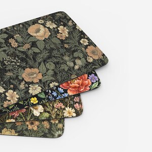 Puede incluir: Tres alfombrillas de rat&oacute;n rectangulares con dise&ntilde;os florales. La alfombrilla superior tiene un fondo oscuro con flores de color beige y verde. La alfombrilla del medio tiene un fondo negro con una gran flor roja. La alfombrilla inferior tiene un fondo oscuro con flores amarillas y beige.
