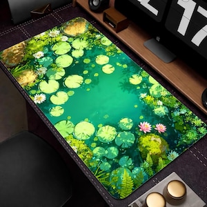May include: A rectangular mouse mat depicting a tranquil pond scene. The design features green lily pads, pink lotus flowers, and verdant foliage set against a vivid green water background. The mat is designed to enhance the aesthetic of a workspace.