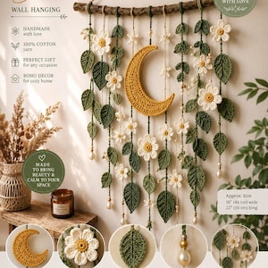 May include: A handmade crochet wall hanging featuring a central yellow crescent moon, white flowers, and green leaves suspended from a wooden branch. The piece includes pearl-like beads and measures 46 cm wide by 56 cm long.