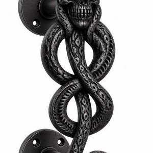 May include: A matte black door handle featuring a detailed human skull at the top, with a long, textured snake winding downwards to form the handle grip, ending in a fanged snake head, all mounted on two circular plates with screw holes.