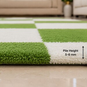 May include: A green and white checkered rug with a textured, tufted surface. A metal ruler is positioned vertically next to the rug, indicating a pile height of 5-6 mm. The rug features a repeating square pattern in alternating colors.