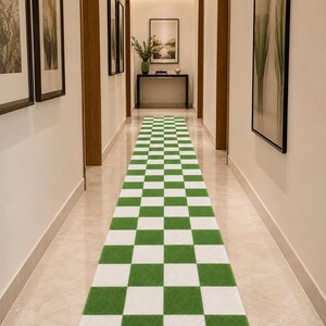 May include: A long rectangular runner rug featuring a repeating checkered pattern of alternating grass green and white squares. The rug is positioned centrally on a polished light-colored floor, extending from the foreground toward the back wall.