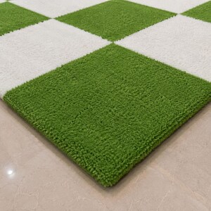 May include: A rectangular area rug featuring a repeating checkered pattern of alternating bright green and white squares. The rug has a thick, textured, tufted pile surface that creates a soft, plush appearance across the entire square grid design.