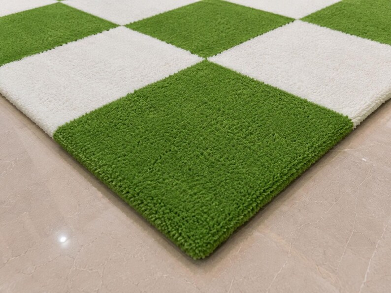 May include: A rectangular area rug featuring a repeating checkered pattern of alternating bright green and white squares. The rug has a thick, textured, tufted pile surface that creates a soft, plush appearance across the entire square grid design.