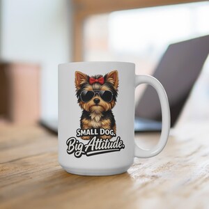 Puede incluir: Taza de cerámica blanca con una ilustración de un Yorkshire Terrier con gafas de sol y un lazo rojo. La taza tiene el texto "SMALL DOG, Big Attitude". La taza está sobre una superficie de madera.