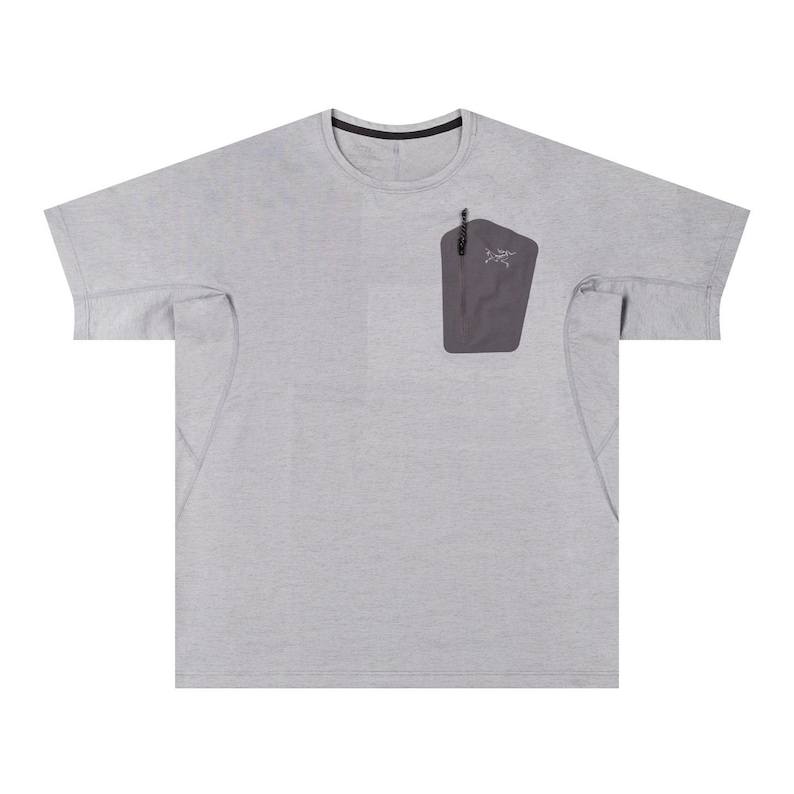 May include: A light gray short-sleeved shirt with a crew neck and a dark gray pocket on the chest. The pocket has a zipper and a small logo. The shirt has a relaxed fit and is made of a lightweight material.