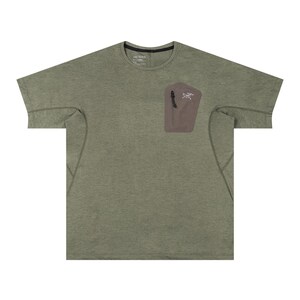 May include: Olive green short-sleeve t-shirt with a small, brown pocket on the chest. The pocket has a zipper and a white logo. The shirt has a crew neck and a relaxed fit.