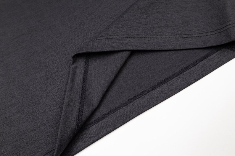 May include: Close-up of a dark gray t-shirt, showcasing the neckline and hem. The fabric has a subtle texture, and the seams are neatly stitched. The image highlights the garment's construction and material.