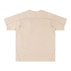 May include: A beige short-sleeved t-shirt with visible stitching details. The shirt has a crew neck and a relaxed fit. The seams are reinforced with a contrasting thread, adding a subtle design element. The fabric appears to be a lightweight material.