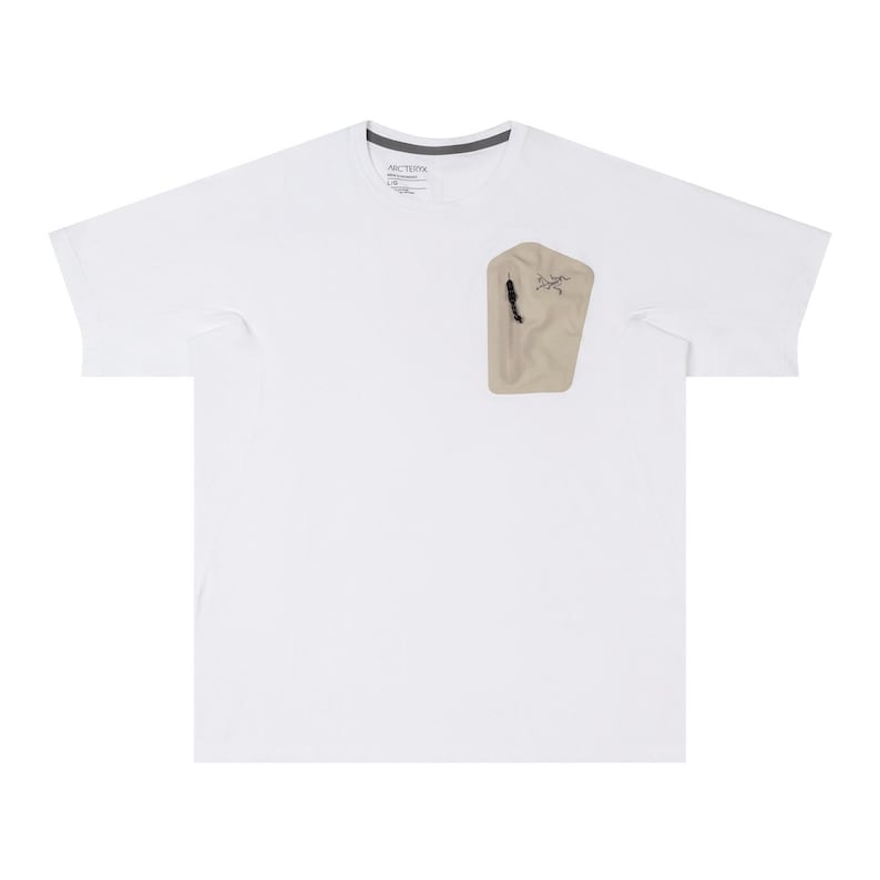 May include: White t-shirt with a beige pocket on the chest. The pocket has a black zipper and a small logo. The shirt has a crew neck and short sleeves. The brand name is visible on the collar.