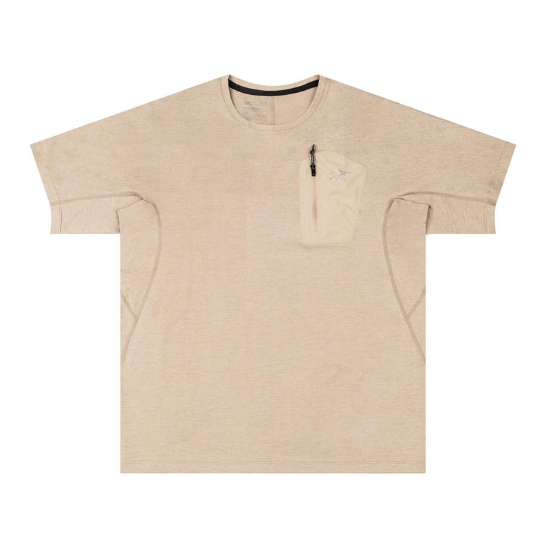 May include: Beige short-sleeved shirt with a small, light-colored pocket on the chest. The shirt has a crew neck with a black trim and a subtle, textured appearance. The pocket features a zipper and a small logo.