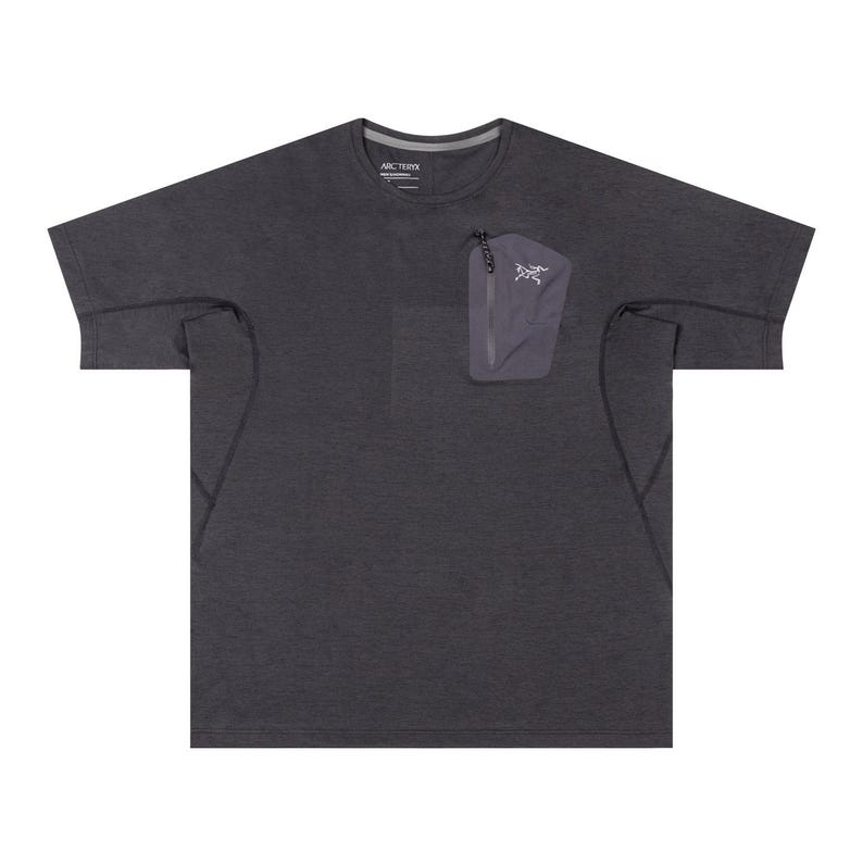 May include: Dark gray short-sleeve shirt with a small zippered pocket on the chest. The pocket is a lighter shade of gray and features a white logo. The shirt has a crew neck and a subtle texture.