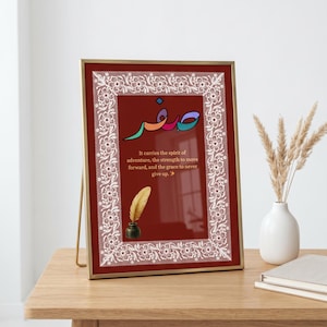 May include: A rectangular picture frame with a thin gold border and a white lace-patterned inner frame. The dark red background features colorful Arabic calligraphy, a gold quill in an inkwell, and the text: It carries the spirit of adventure, the strength to move forward, and the grace to never give up.